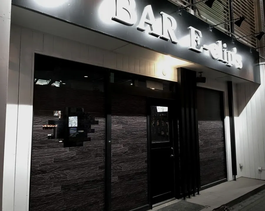 夜の外観。「BAR E-clip's」の立体文字の看板がスポットライトに照らされている